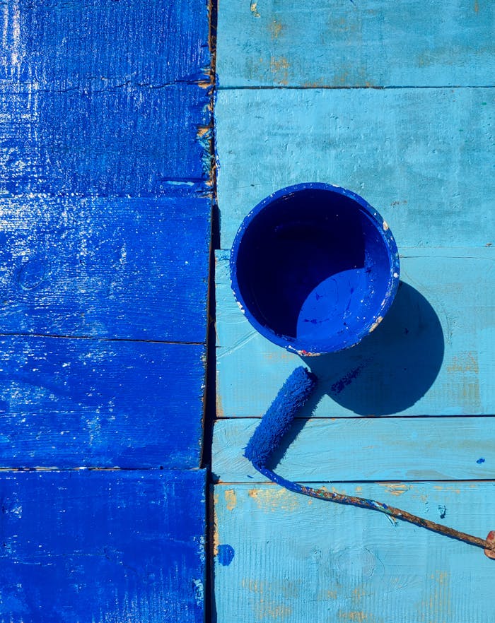 why-choose-us A striking image of blue paint and roller on wooden boards, showcasing vibrant creativity.