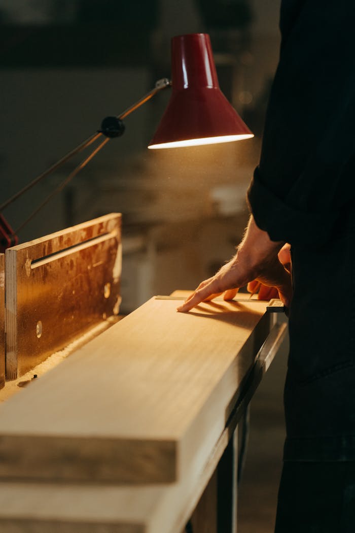 our-journey-03 A skilled craftsman handcrafting wood under warm light in a workshop, focusing on precision.